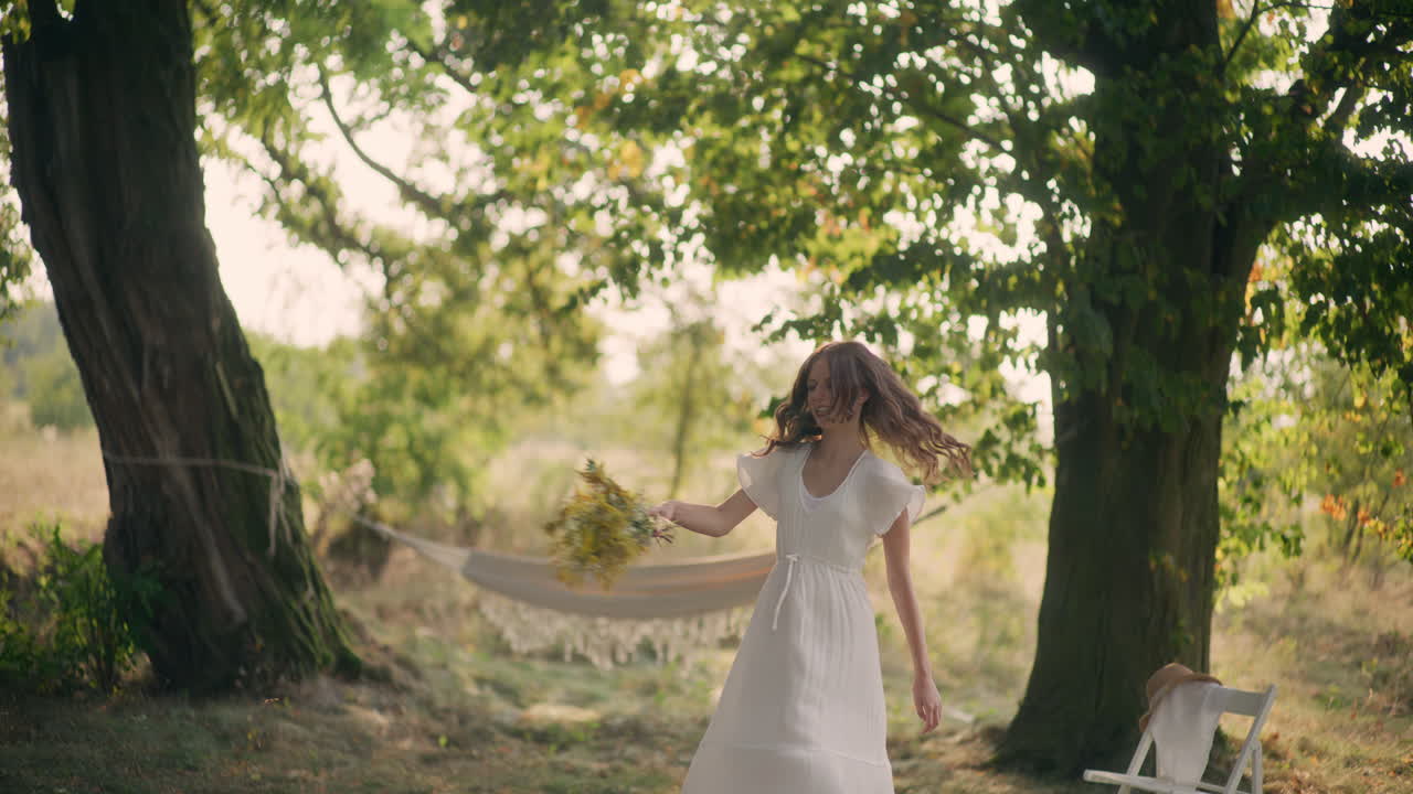 Joyful girl dancing with flowers at sunset