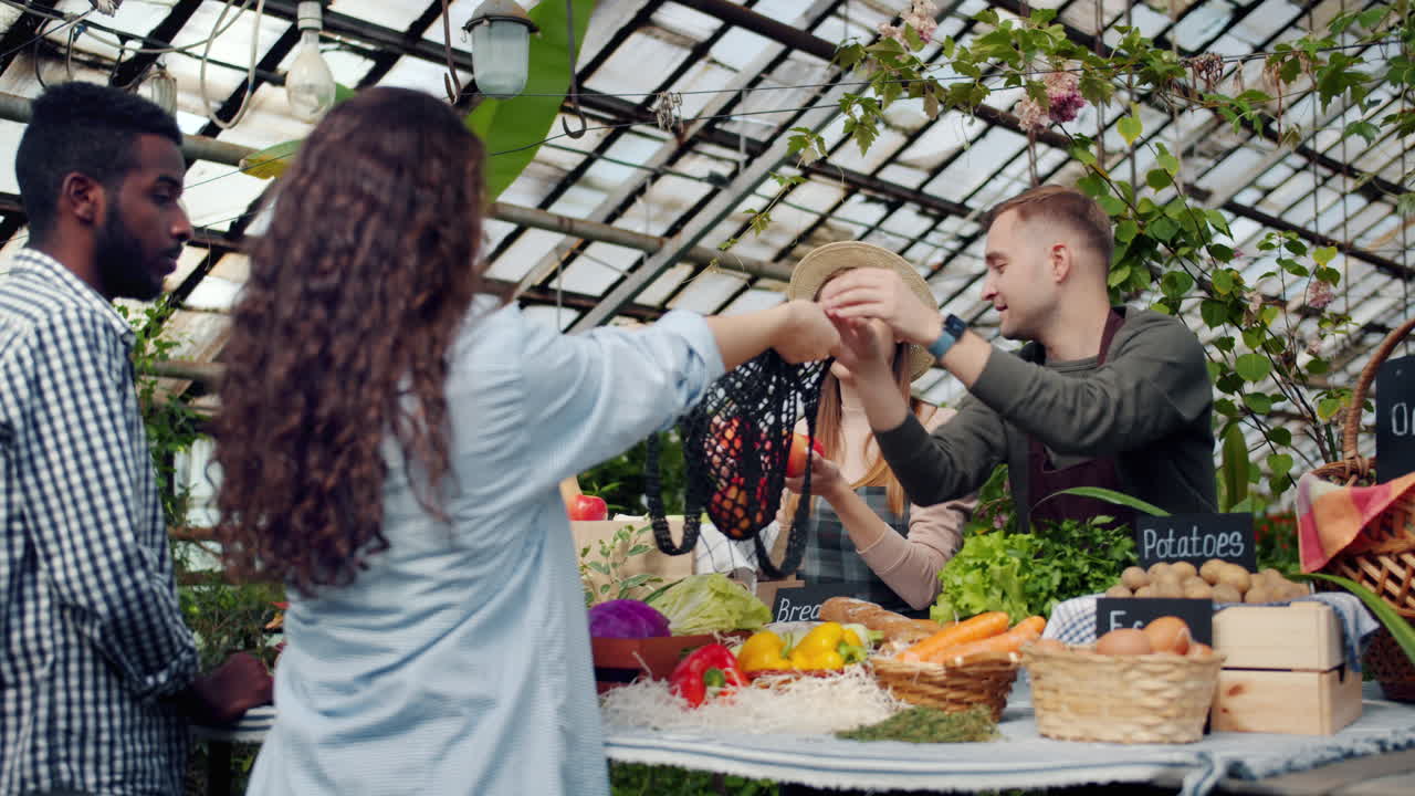 People shopping at a local farmers market in a greenhouse