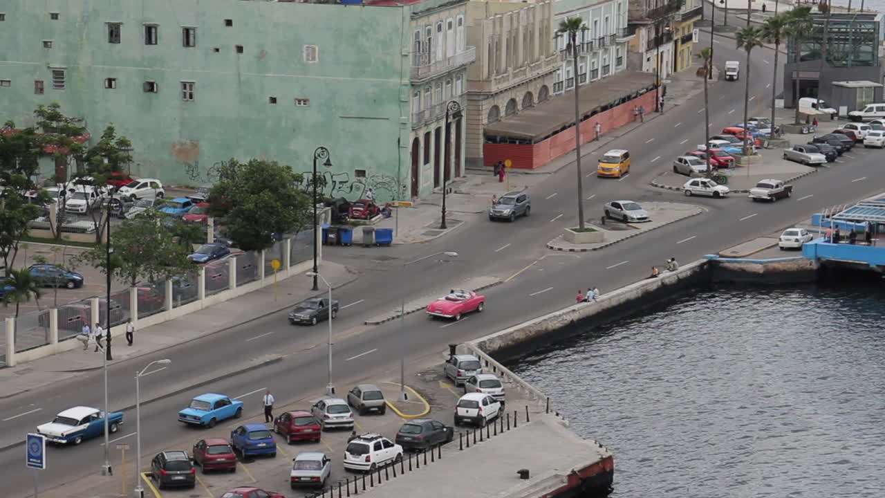 Overhead view of a busy city street with classic cars and a waterfront