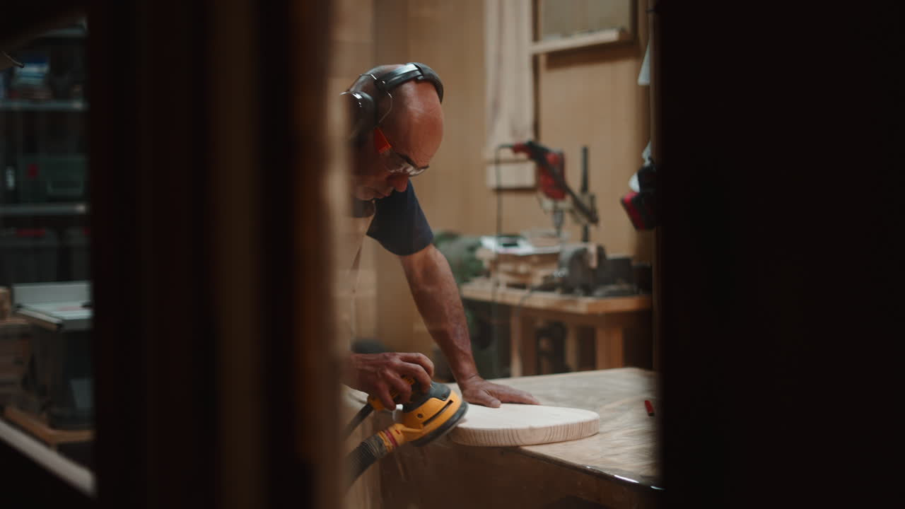 Skilled Woodworker Sanding Wood with Orbital Sander in Workshop