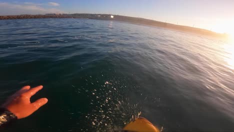 pov of a surfer standing and balancing on a board, catching some waves, surf foiling in the sea at sunrise in caparica beach