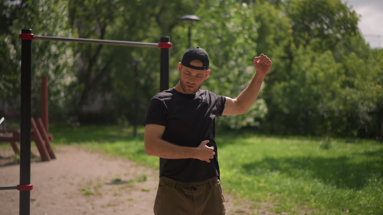 Dynamic Workout Scene, Energetic Individual Performing Torso Swings Beside Exercise Bars In Sunlight, Outdoor Fitness Enthusiast Engaging In Dynamic Arm Swings During Warmup Before Training Session
