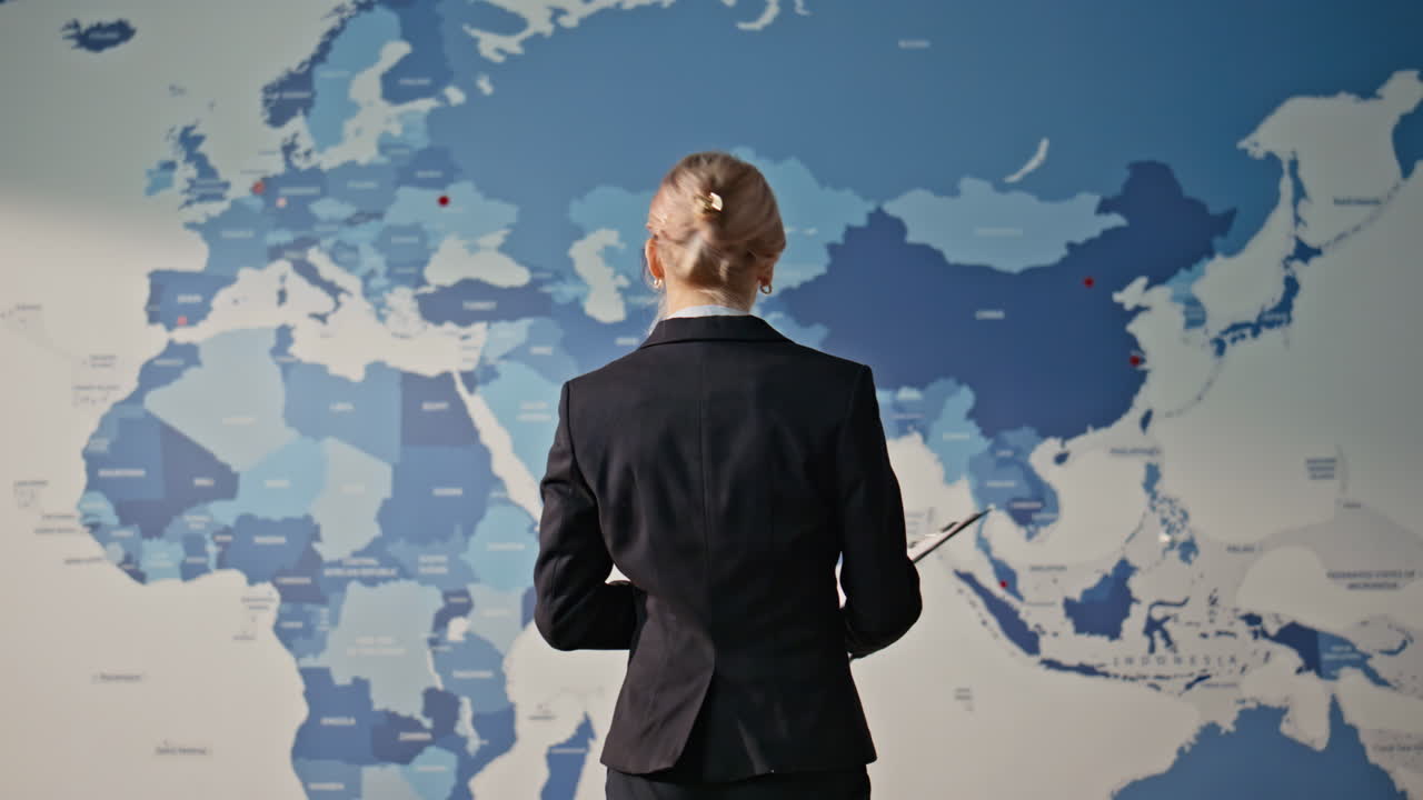 Woman examining world map monitoring office back view. Business analyst working