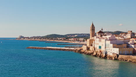 drone rises above charming old church in sunny weather with a beautiful blue sea coast backdrop