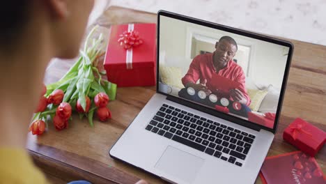 Fröhlicher-Afroamerikanischer-Mann,-Der-Ein-Geschenk-öffnet-Und-Einen-Videoanruf-Zum-Valentinstag-Auf-Dem-Laptop-Tätigt