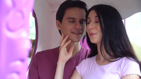 pareja enamorada sentada en un carruaje de calabaza en un carrusel tomándose de la mano y besándose juntos en el parque de atracciones al aire libre en verano divirtiéndose en vacaciones