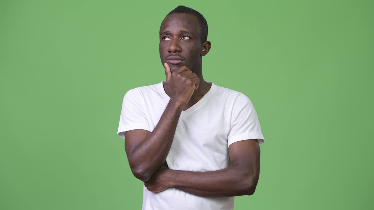 Young African man thinking against green background