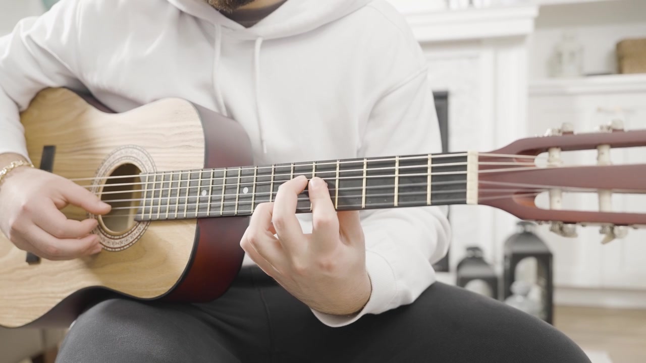 Primo piano frontale di un giovane uomo che suona una chitarra classica.