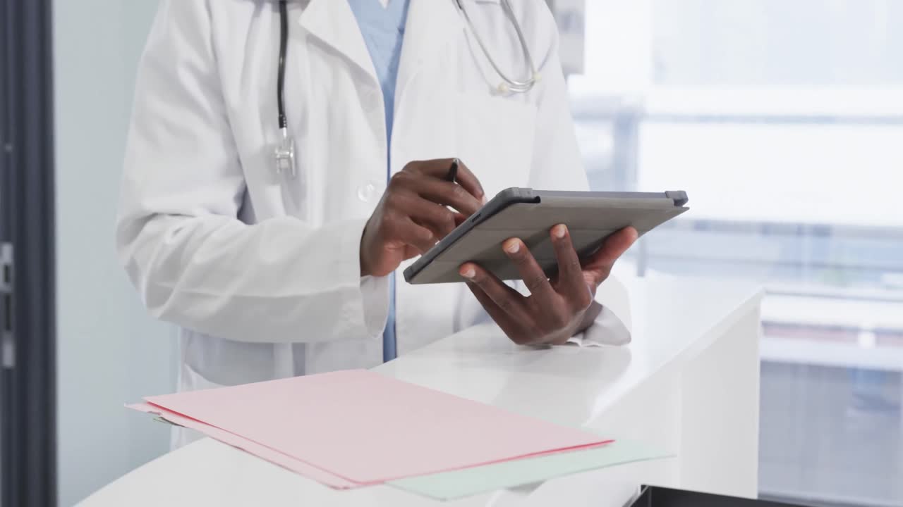 Busto di medico afroamericano che usa un tablet in ospedale, al rallentatore