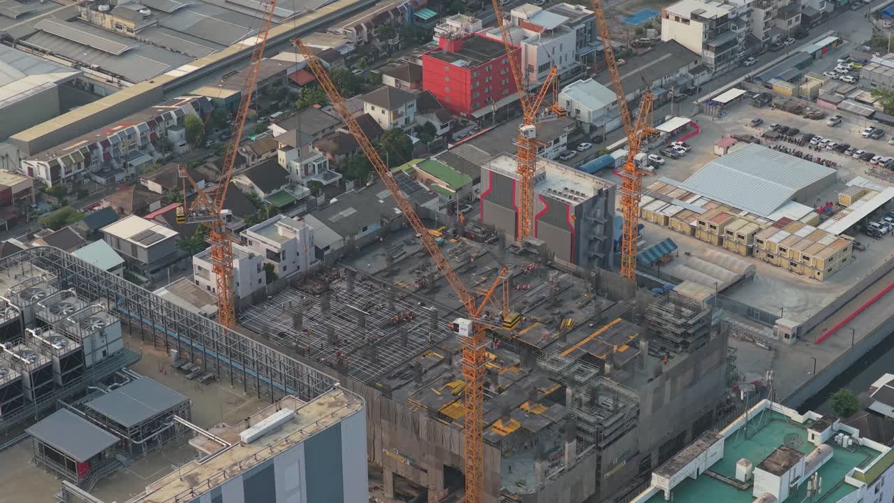 Pemandangan udara lokasi konstruksi besar di area perkotaan. Beberapa derek menara aktif membangun struktur gedung bertingkat tinggi yang baru