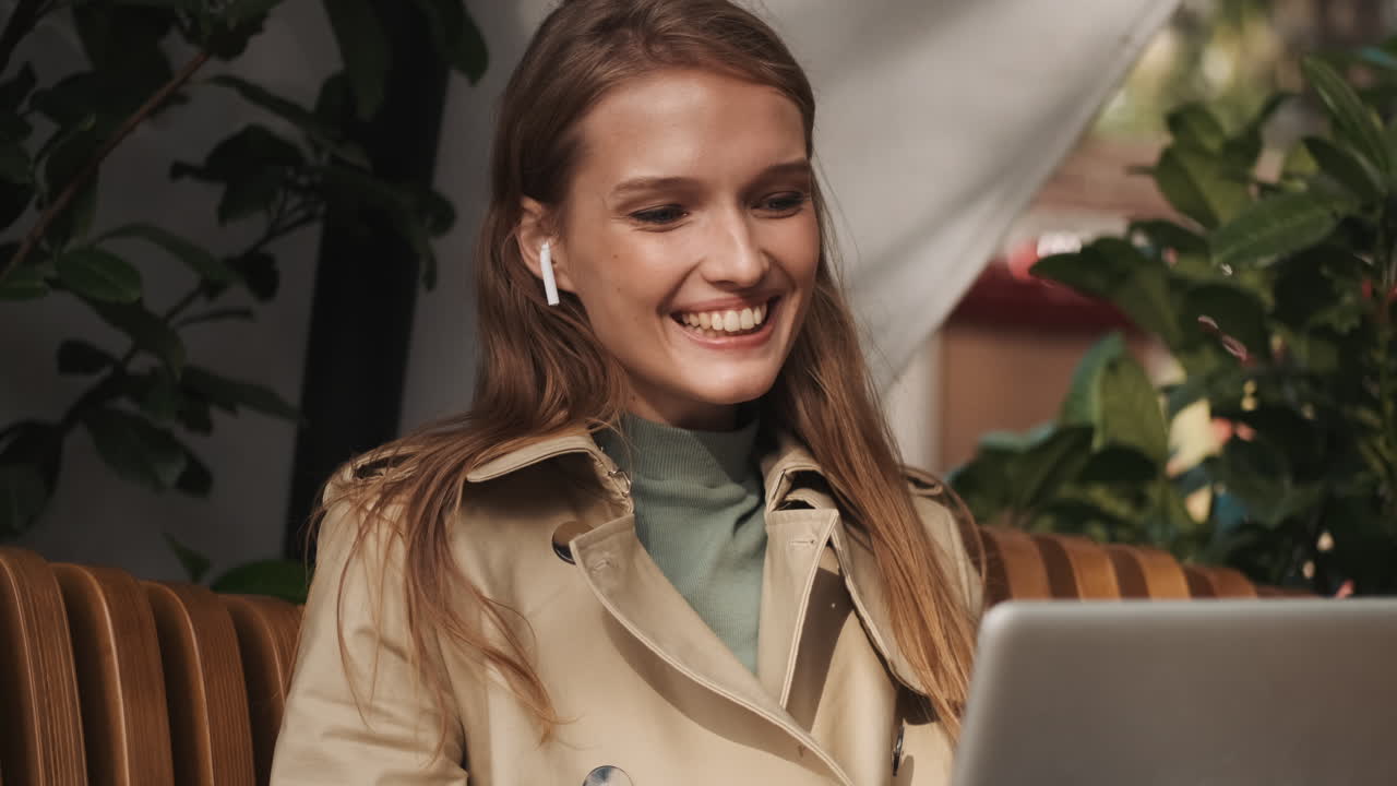 Caucasian female video calling on laptop outdoors.