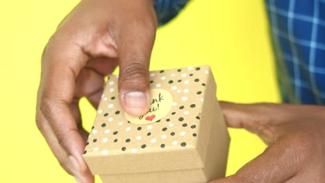 person giving a gift box with a thank you sticker