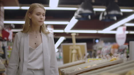 attractive girl customer is buying bread in bakery department is shop smelling it smiling and putting in shopping trolley. healthy lifestyle and supermarket concept.