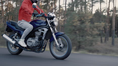 motorcyclist rides along forest on cloudy day 1