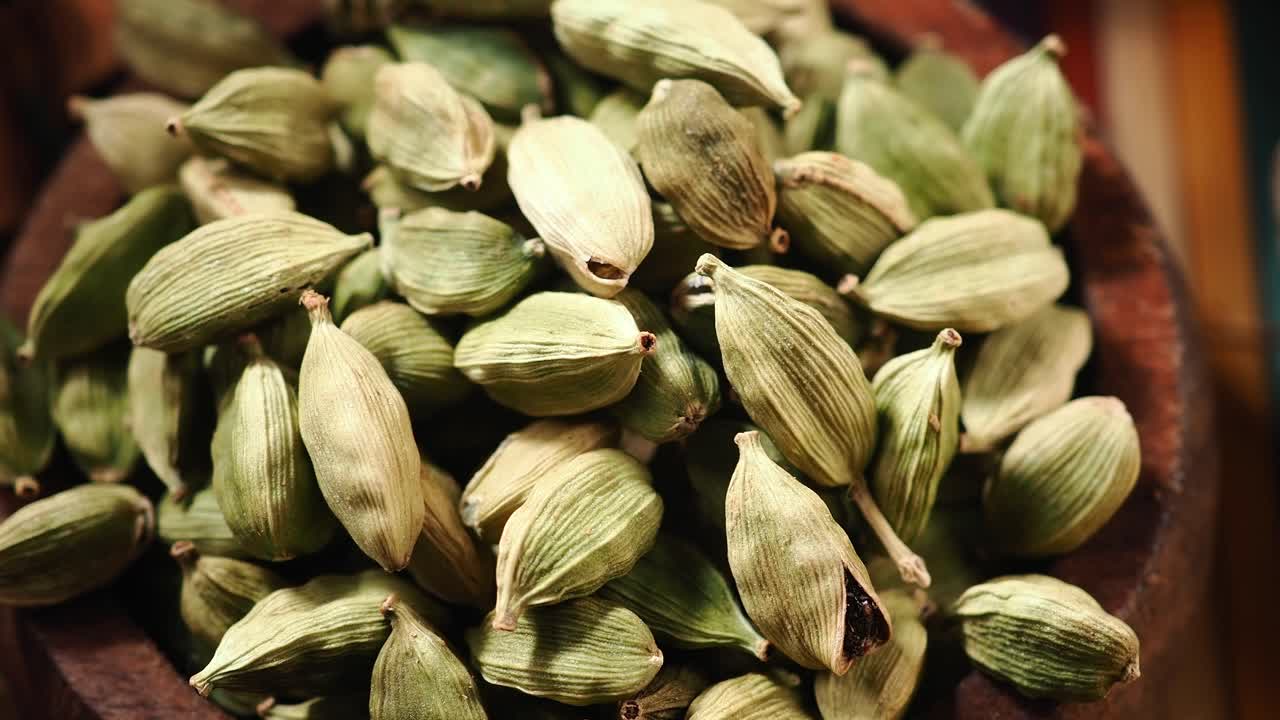 Primo piano di baccelli di cardamomo verde in una ciotola di legno