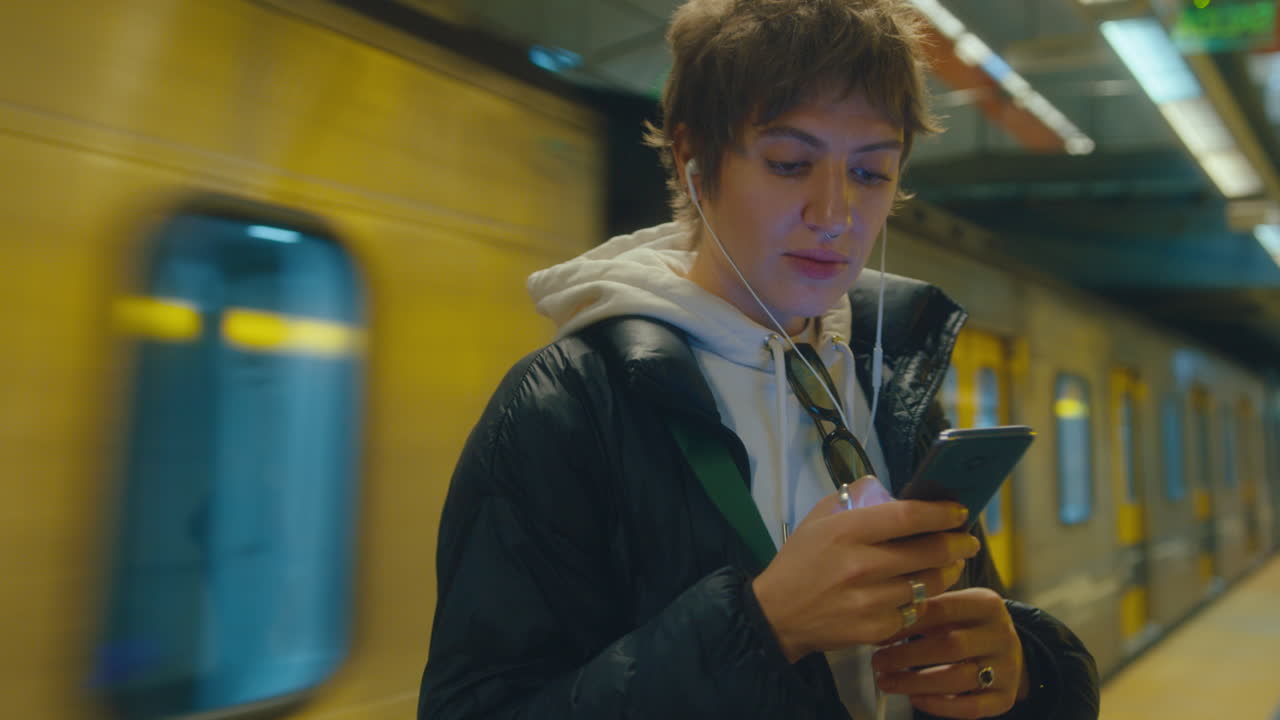 Young Woman Using Mobile Phone on Subway Platform