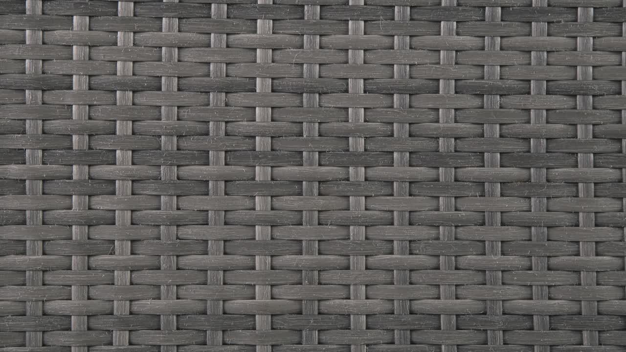 Camera closes in on rich wicker weave of patio chair under daylight