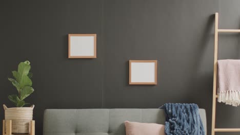 Wooden-frames-with-copy-space-on-white-background-with-plant-and-sofa-against-grey-wall