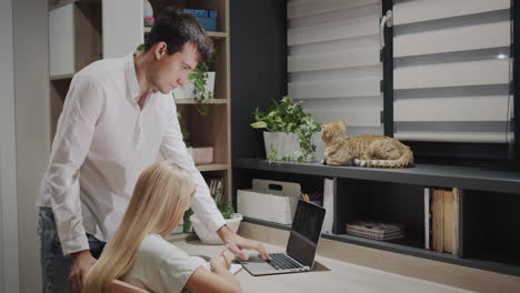 the older brother helps his sister with homework, their cat is sitting next to him. study at home