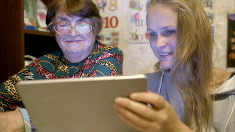 young and senior woman looking through photos on pad