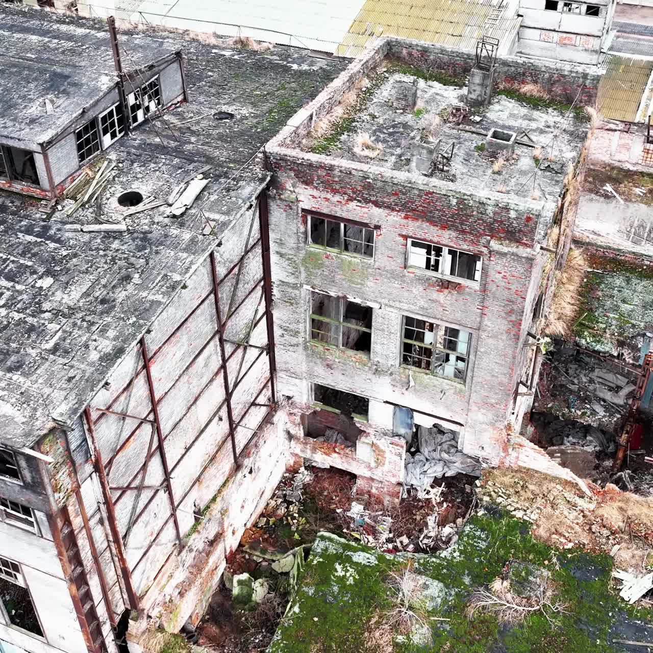 Debris and construction garbage inside and outside the broken factory buildings. Ruined plant exterior from aerial perspective