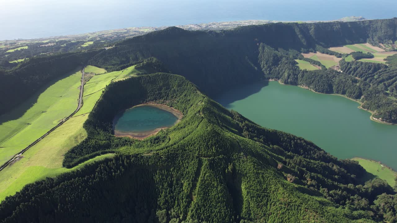 Sete Cidades crater with Lagoa Rasa and Lagoa Verde revealed as the view moves left and opens toward the ocean on Sao Miguel island in the Azores