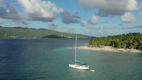 People-on-board-of-moored-sailboat-on-transparent-seawater-of-Cayo-Levantado,-Samana