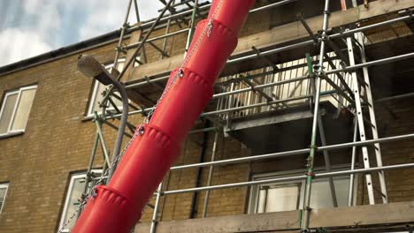 Red-scaffolding-debris-rubble-slide,-London-building-house-under-construction-or-renovation