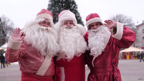 portrait of happy senior men in costumes of santa claus on the background of the christmas tree portrait of happy senior men in costumes of santa claus on the background of the christmas tree santa greets passersby christmas mood concept