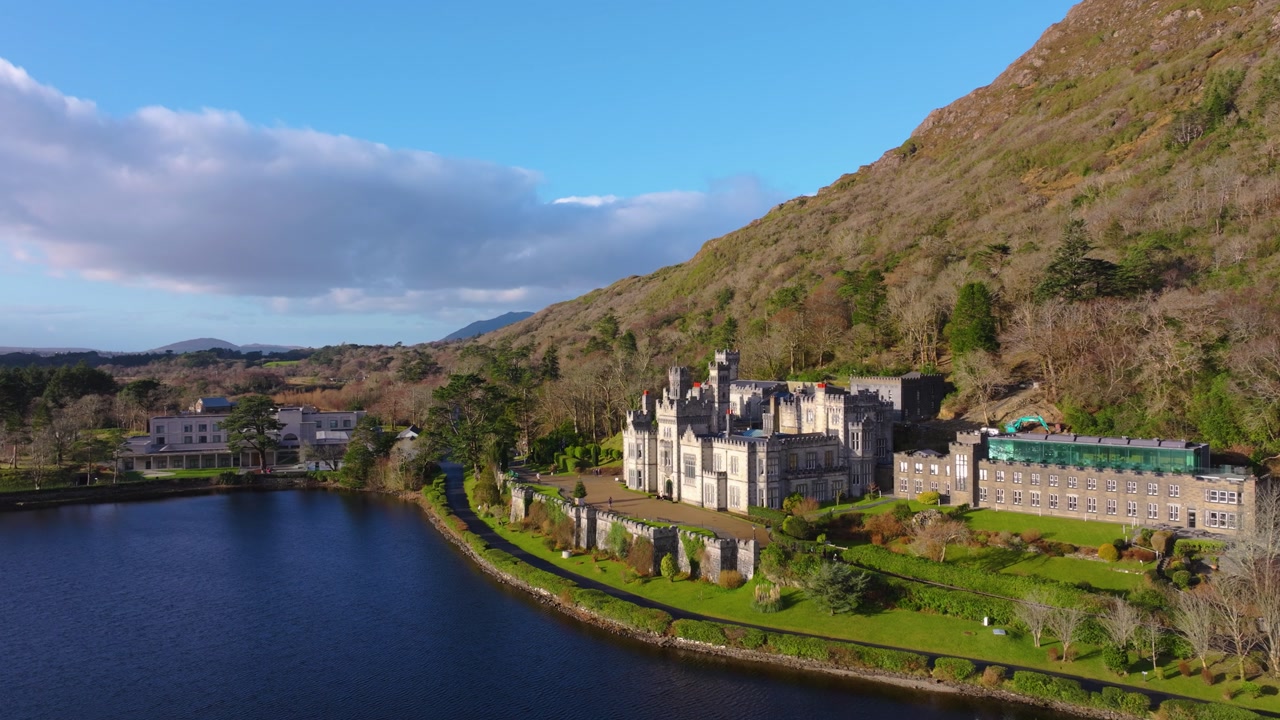 4K Cinematic Drone footage of Kylemore Abbey featuring calm water, mountain backdrop, and clear sunny conditions. Scenic and peaceful Irish landscape_10