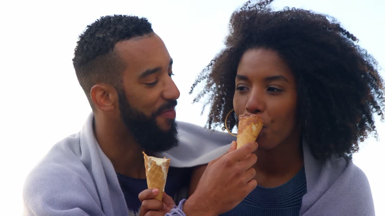 Couple eating ice cream cone at beach 4k