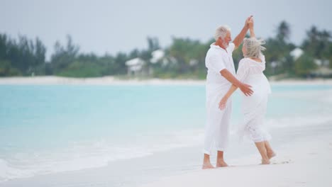retired caucasian couple dancing on caribbean vacation beach