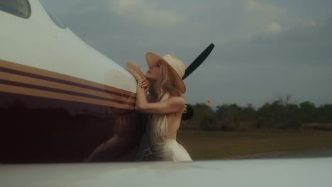 woman in straw hat by airplane