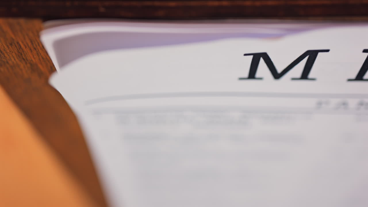 Close up of a menu, with the word "MENU" prominently displayed in bold clipped together using a black binder clip