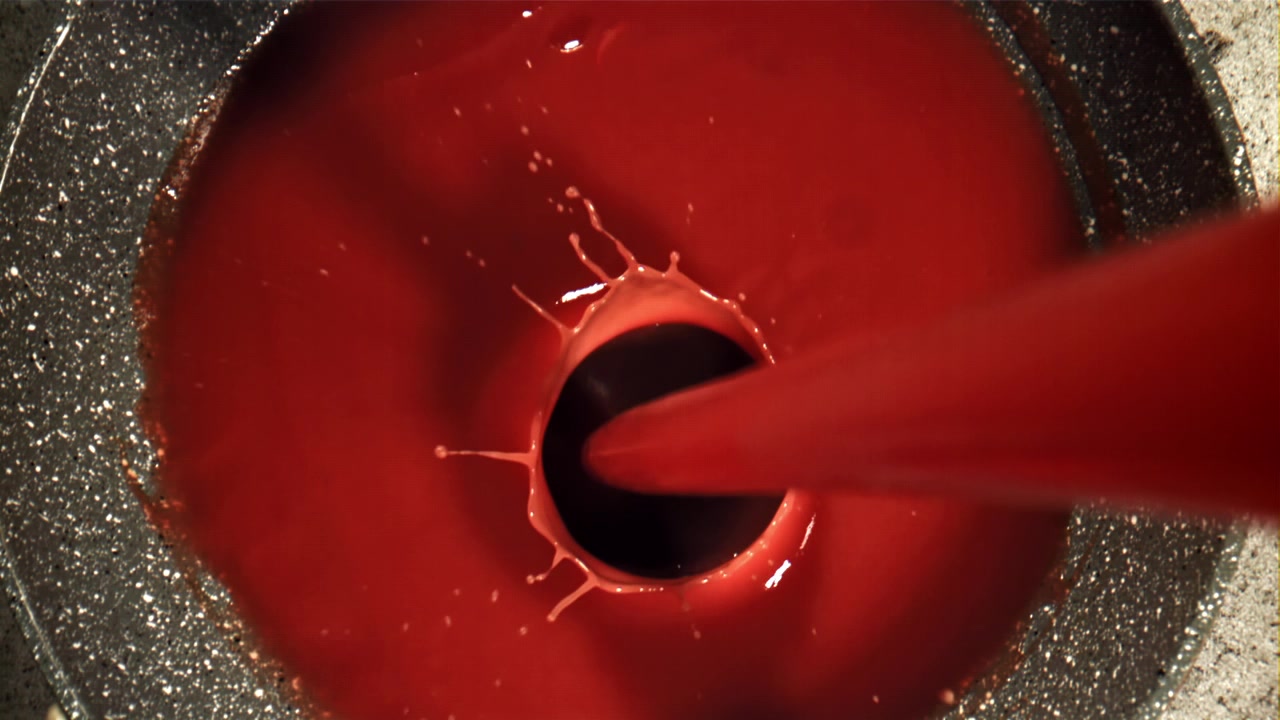 Primo piano di densa salsa rossa che si versa in una padella
