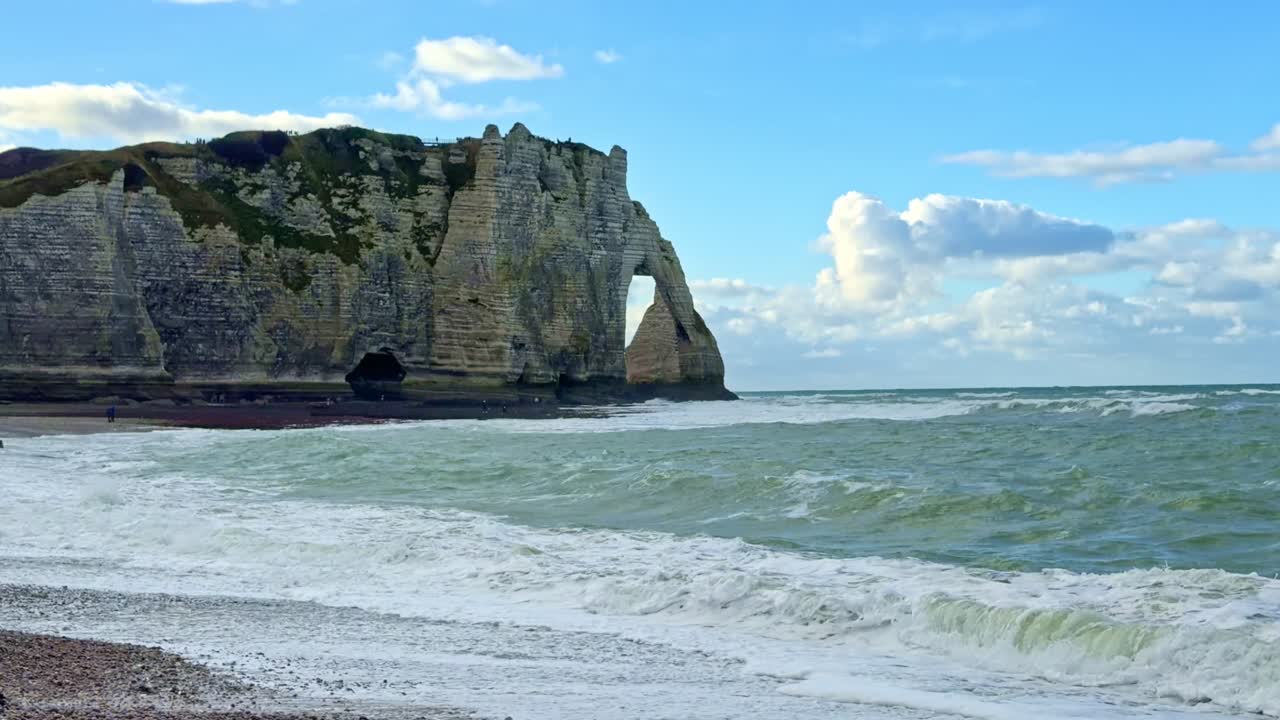 Static coastal view of Etretat arch, chalk cliffs, waves and pebble beach in Normandy
