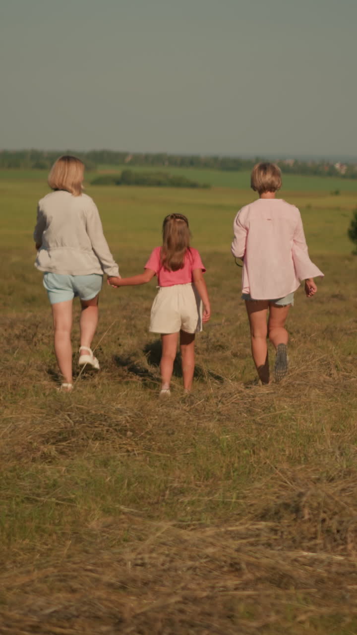 작은 아이는 먼 곳을 가리키는 이모와 함께 걸어가고, 다른 여자가 줄을 들고 는 동안, 개는 울창한 초록색으로 광활한 농장을 가로질러 자유롭게 달린다.