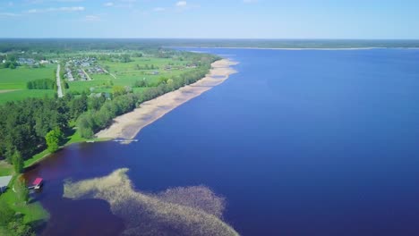 Aerial-panorama-view-of-a-Lake-Usma-on-a-sunny-summer-day,-distant-islands-with-lush-green-forest,-coastal-reeds,-beautiful-rural-landscape,-wide-angle-drone-shot-moving-right