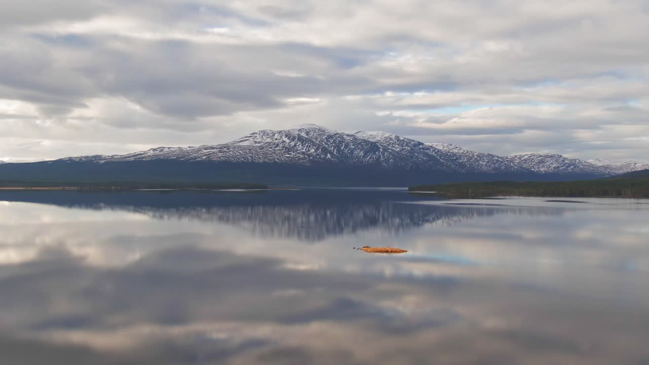 disparo de drones de paralaje del lago sueco con montañas nevadas y cielo nublado
