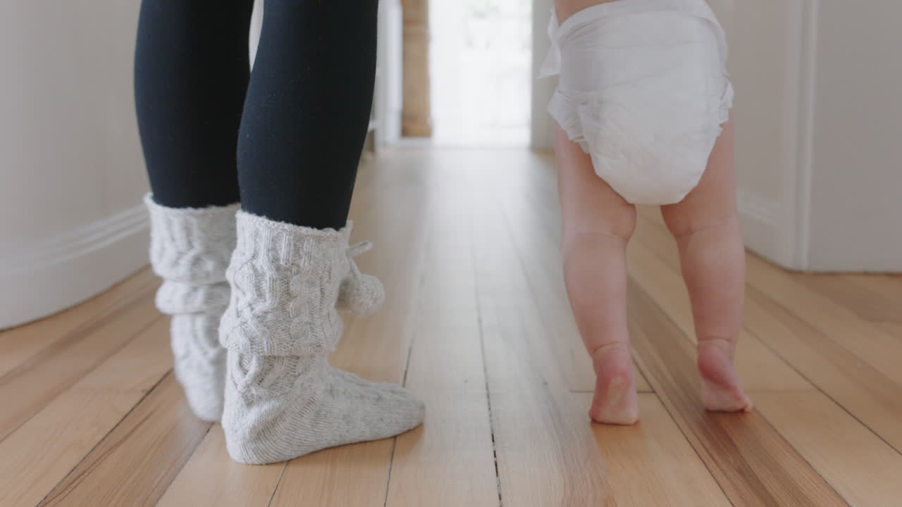 bebé aprendiendo a caminar niño pequeño dando sus primeros pasos con la madre ayudando al bebé enseñando al niño en casa