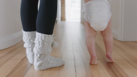 baby learning to walk toddler taking first steps with mother helping infant teaching child at home