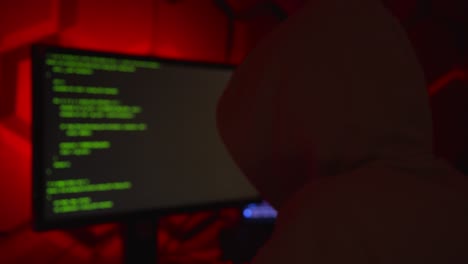 hacker anonimo in un codice di scrittura con cappuccio