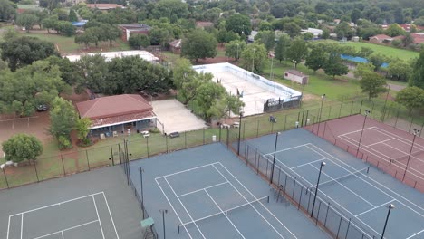 lenta derecha y hacia arriba inclinación tiro aéreo de las canchas de tenis de un viejo club de tenis revelando el resto de la ciudad