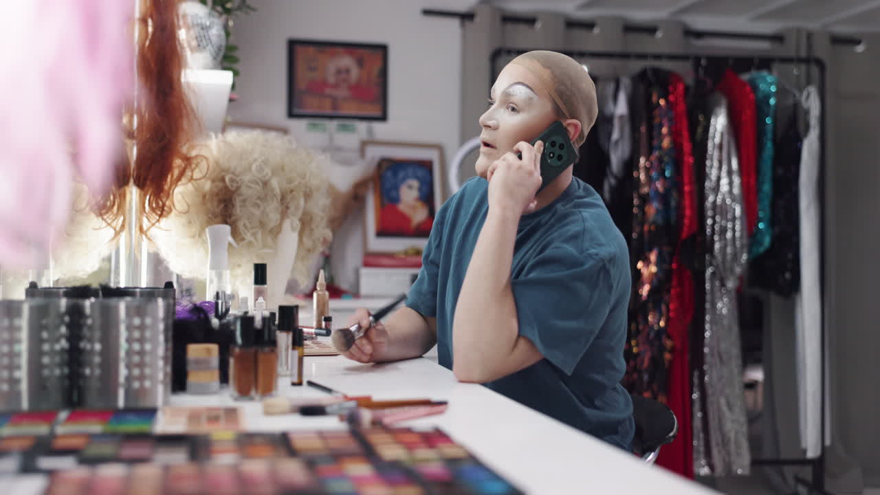 Dragqueen telefoniert und schminkt sich dabei