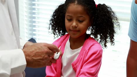 Male-doctor-interacting-with-patient-while-checking-temperature-on-thermometer