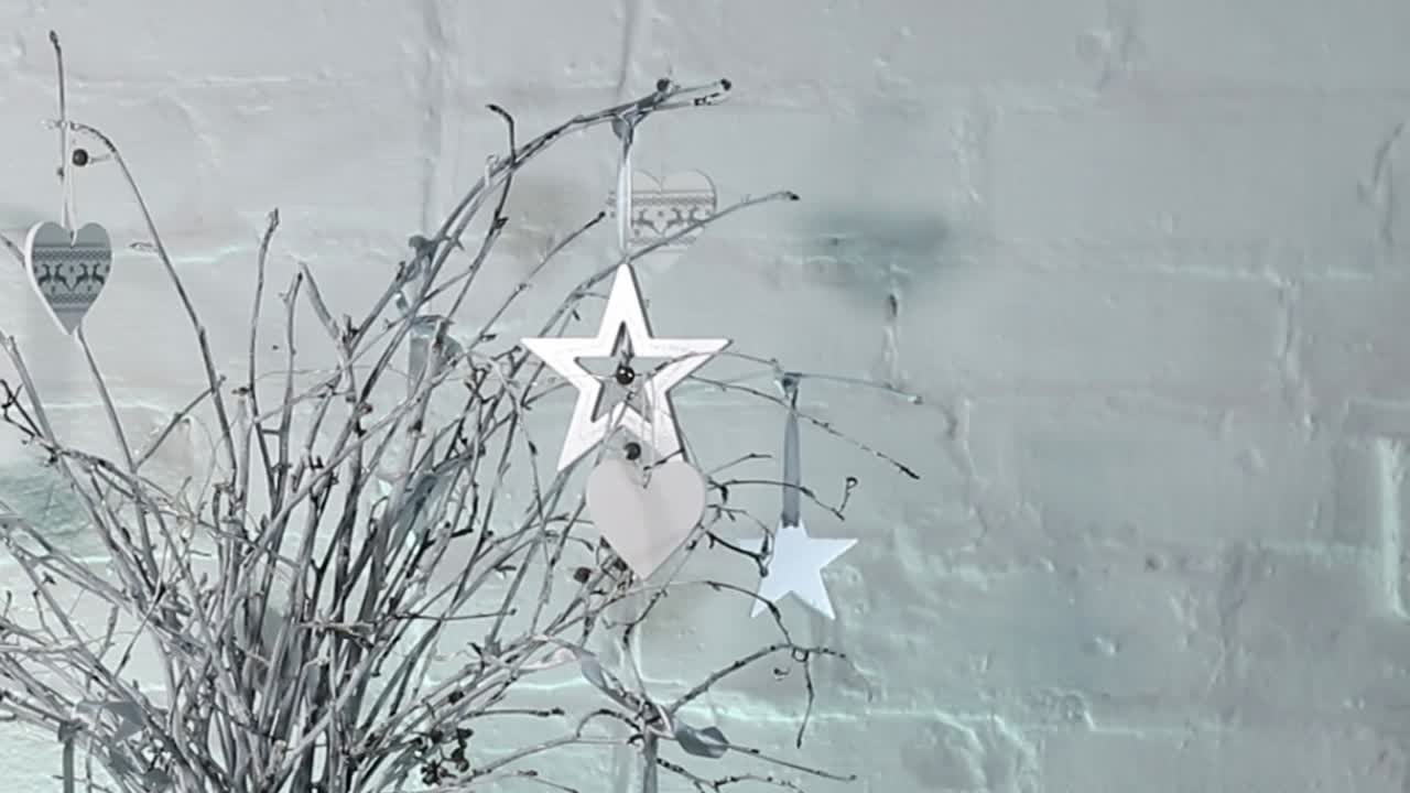 Christmas Table centre piece with white painted twigs in a glass vase with fairy lights, hearts and stars.