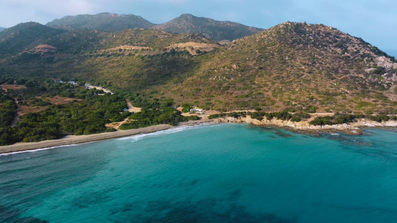 Idyllic Sardinia clear blue turquoise and calm water at a natural sand beach coast bay in Italy with sun and sailing boat