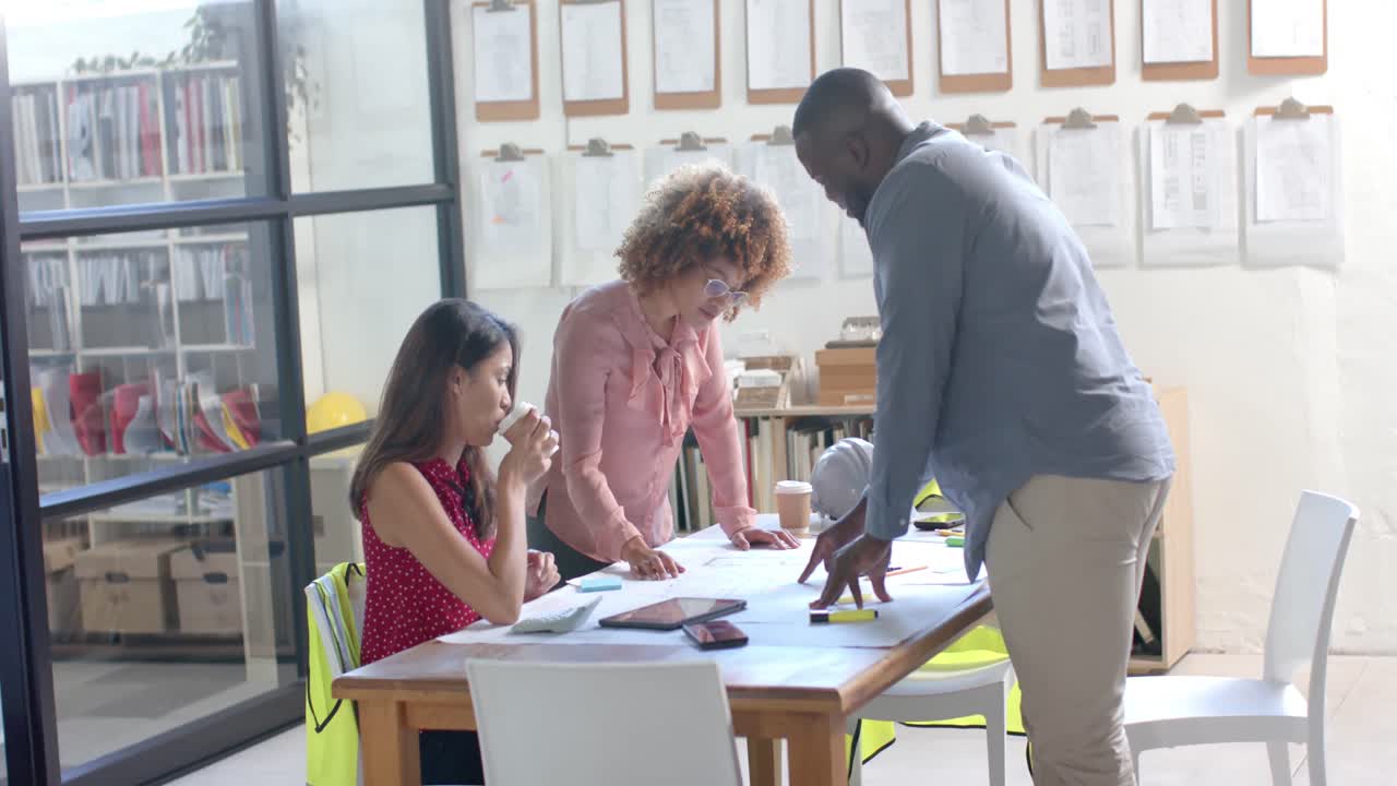 Busy diverse architects discussing blueprints on table in office, slow motion