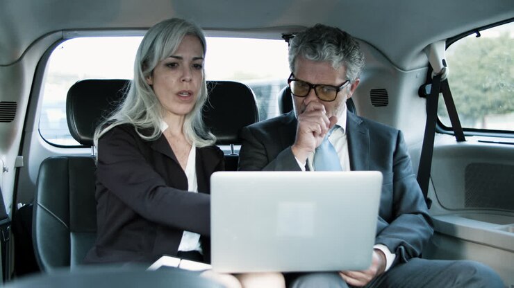 Partner commerciali che lavorano insieme usando un laptop in auto