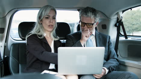 business partners working together using laptop in car